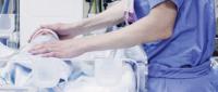 A healthcare worker attends to a newborn in an incubator.